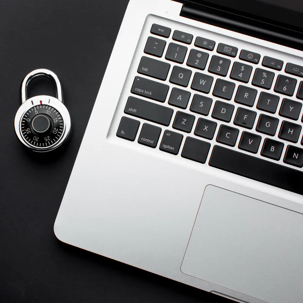 Combination padlock beside a laptop keyboard on dark background